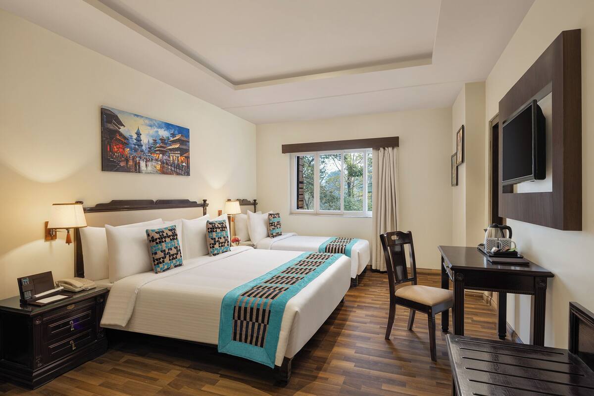 Une chambre d’hôtel avec deux lits, un bureau, une chaise, une télévision et un tableau au mur.