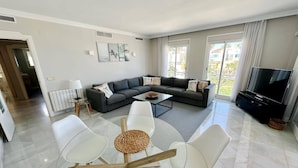Una sala de estar moderna con un sofá modular, una mesa de centro y un televisor.