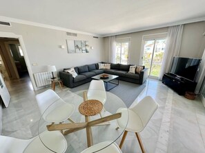 A modern living room with a sectional sofa, a coffee table, and a TV.