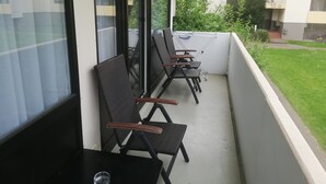 A balcony with four wicker chairs and a small table, overlooking a grassy area and a building with balconies. - Ruhige Ferienwohnung/ Amateurzimmer/ Gute Verkehrsanbindung (Linden)