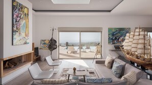 Ein modernes Wohnzimmer mit großem Fenster, einem Segelbootmodell und verschiedenen Kunstwerken.