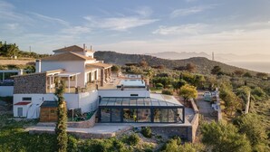 Eine moderne Villa mit Swimmingpool, Wintergarten und Blick auf die umliegenden Hügel.
