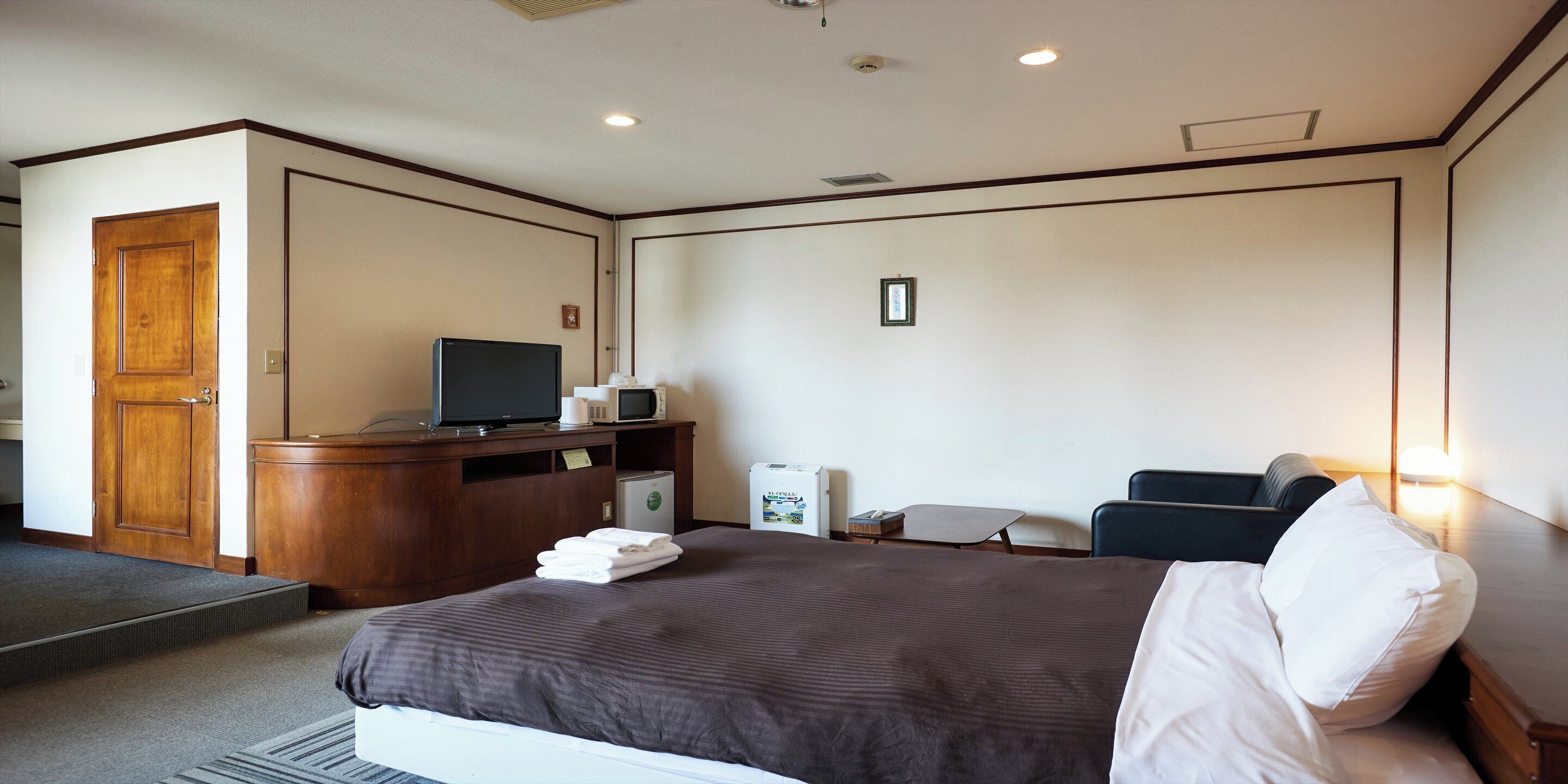 A hotel room with a bed, a desk with a computer, a television, and a microwave.
