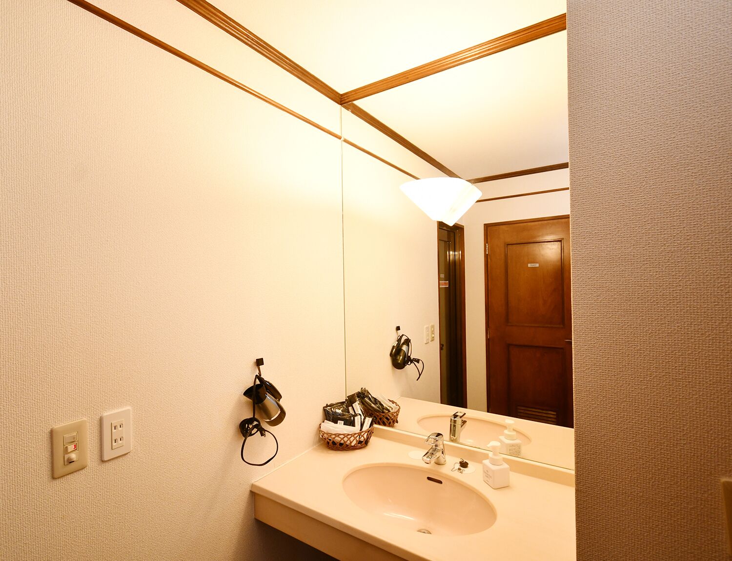 Une salle de bain avec un lavabo, un miroir et une porte en bois.