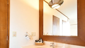 A bathroom with a white sink, a mirror, and a light fixture above it. - Purari (Okinawa)