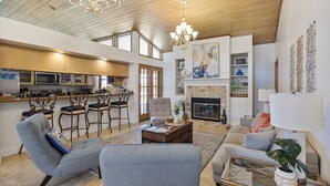 A spacious living area with a fireplace, a kitchen with modern appliances, and a dining area with bar stools. - Beautiful River Front Home - Private Pool - Walk to Beach-Kayaks (Cocoa Beach)