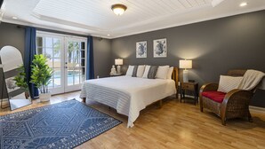 A bedroom with a large bed, a chair, a nightstand, a lamp, and a view of the outdoors. - Beautiful River Front Home - Private Pool - Walk to Beach-Kayaks (Cocoa Beach)