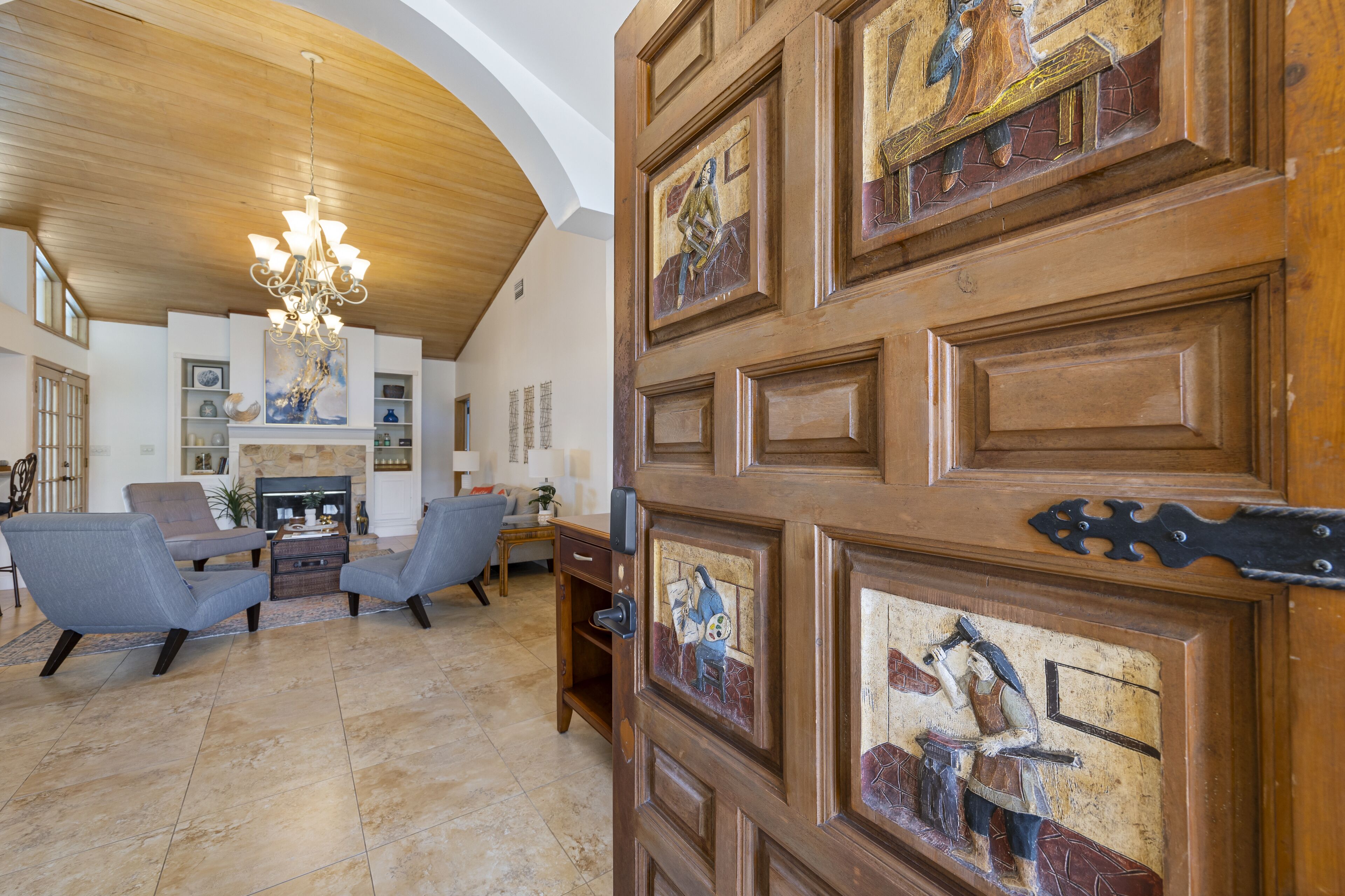Un ampio soggiorno con camino, posti a sedere confortevoli e una porta in legno con pannelli decorativi.