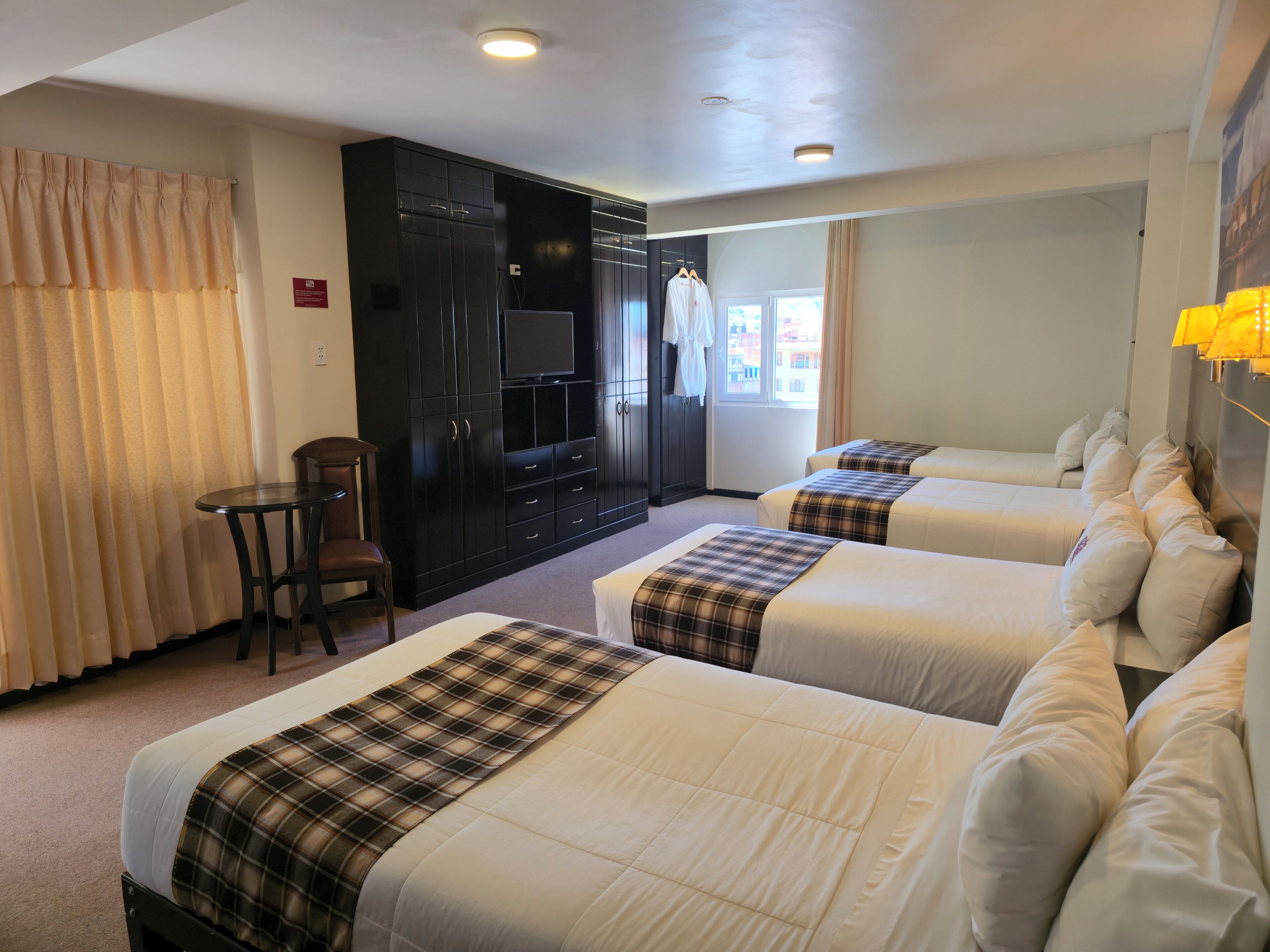 A hotel room with two beds, a TV, a desk, and a chair.