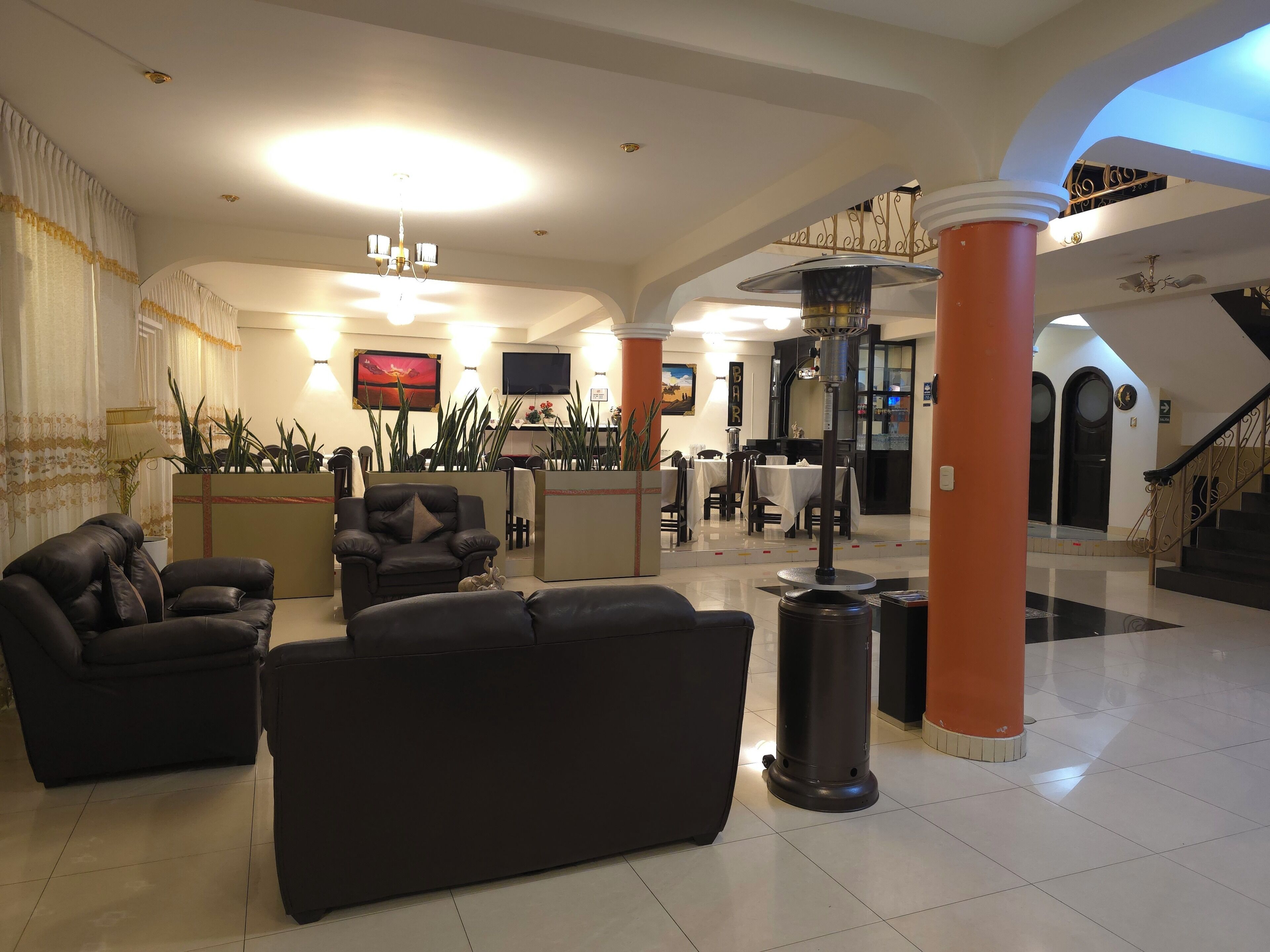 A hotel lobby with leather sofas, a reception desk, a bar area, and a staircase.