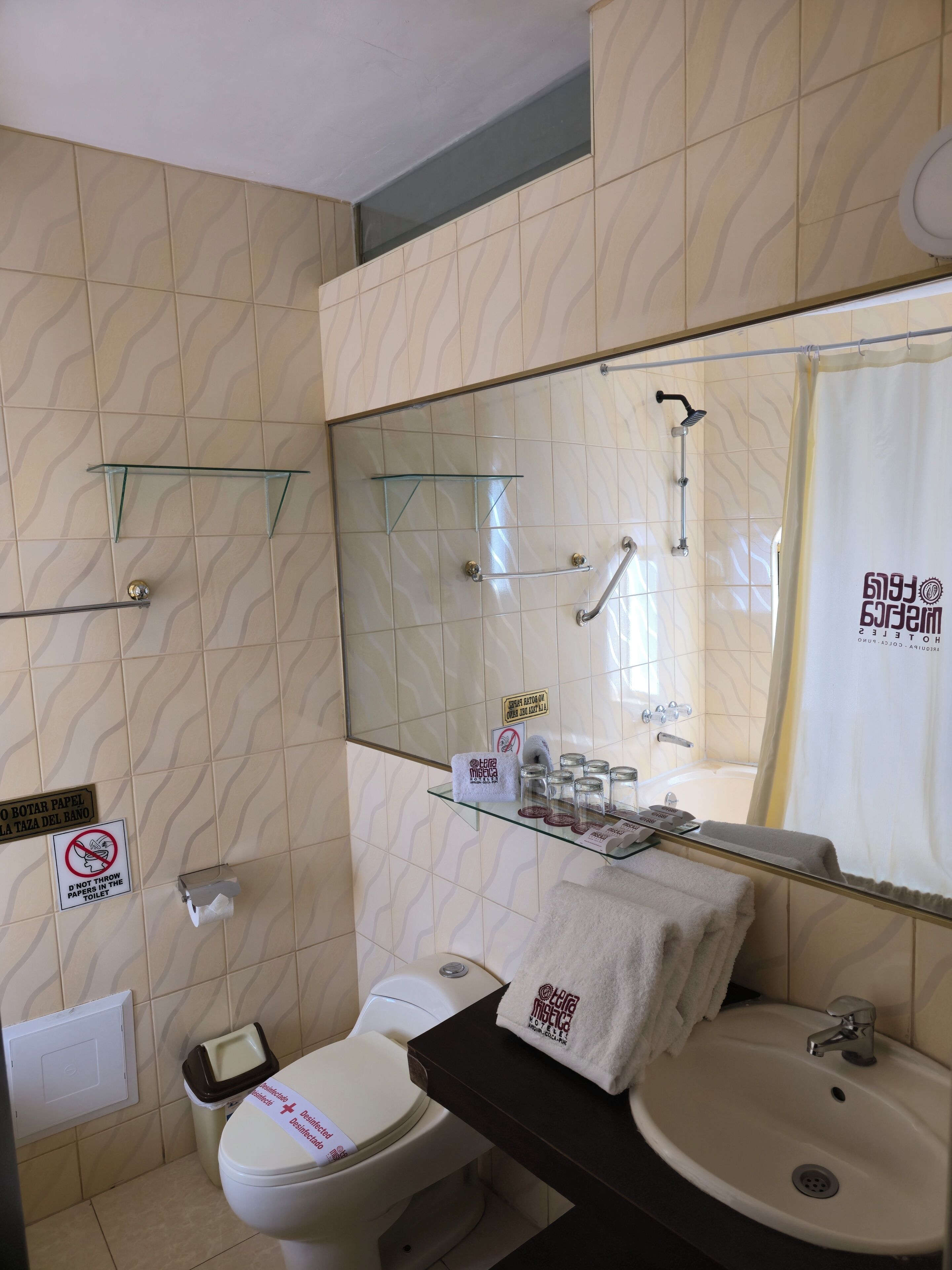 A bathroom with a toilet, sink, glass shower enclosure, and a mirror.