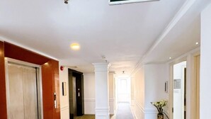 A hotel corridor with an exit sign, a carpeted floor, and a column. - Aodai Inn Saigon (Ho Chi Minh City)