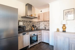 Une cuisine dotée d’appareils électroménagers en acier inoxydable, de meubles en bois, d’un crédence décorée et d’un tableau accroché au mur.