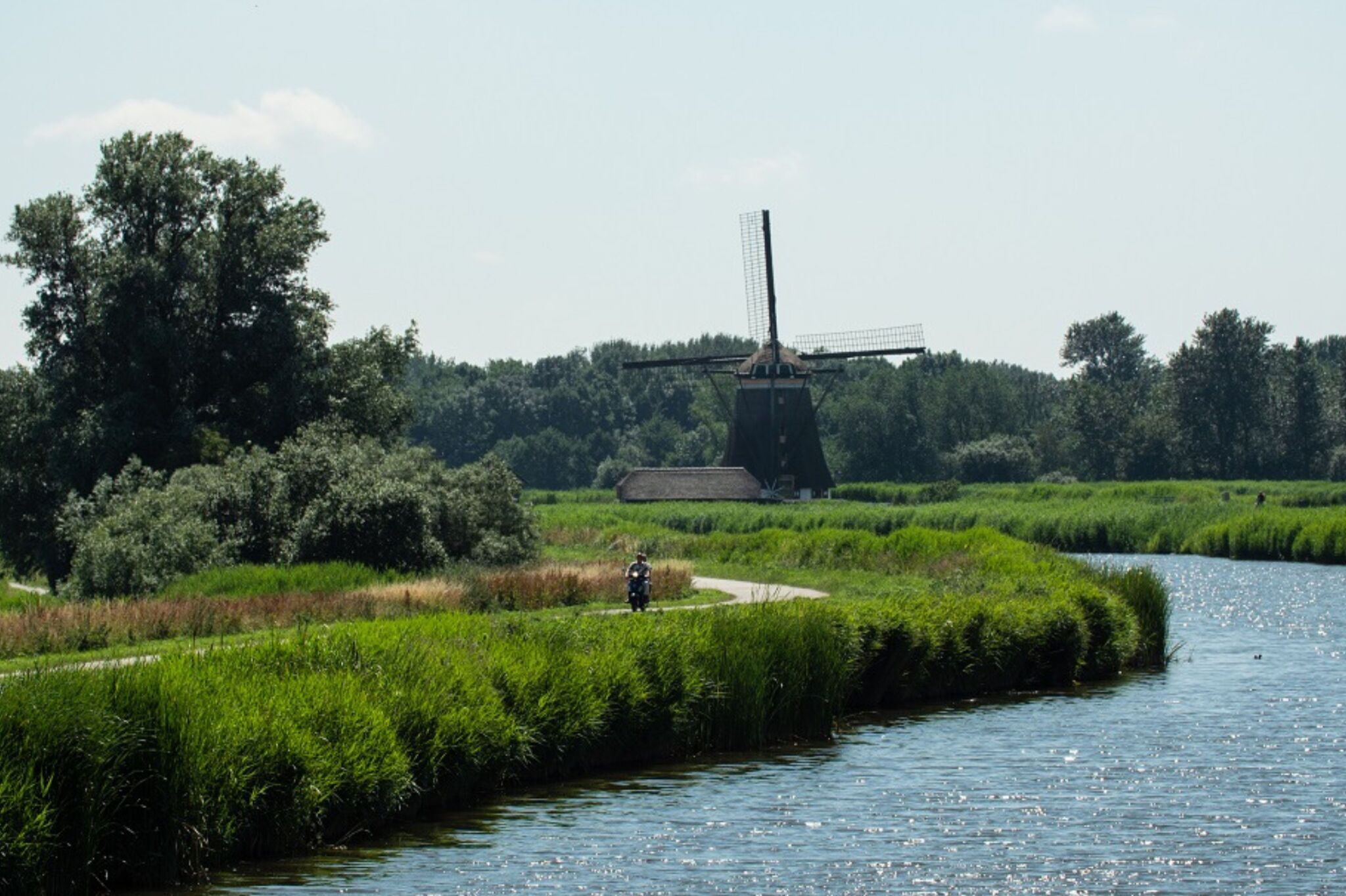 Un molino de viento en un paisaje verde y exuberante con un río.