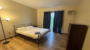 Una habitación con cama, escritorio, lámpara y ventana con cortinas.