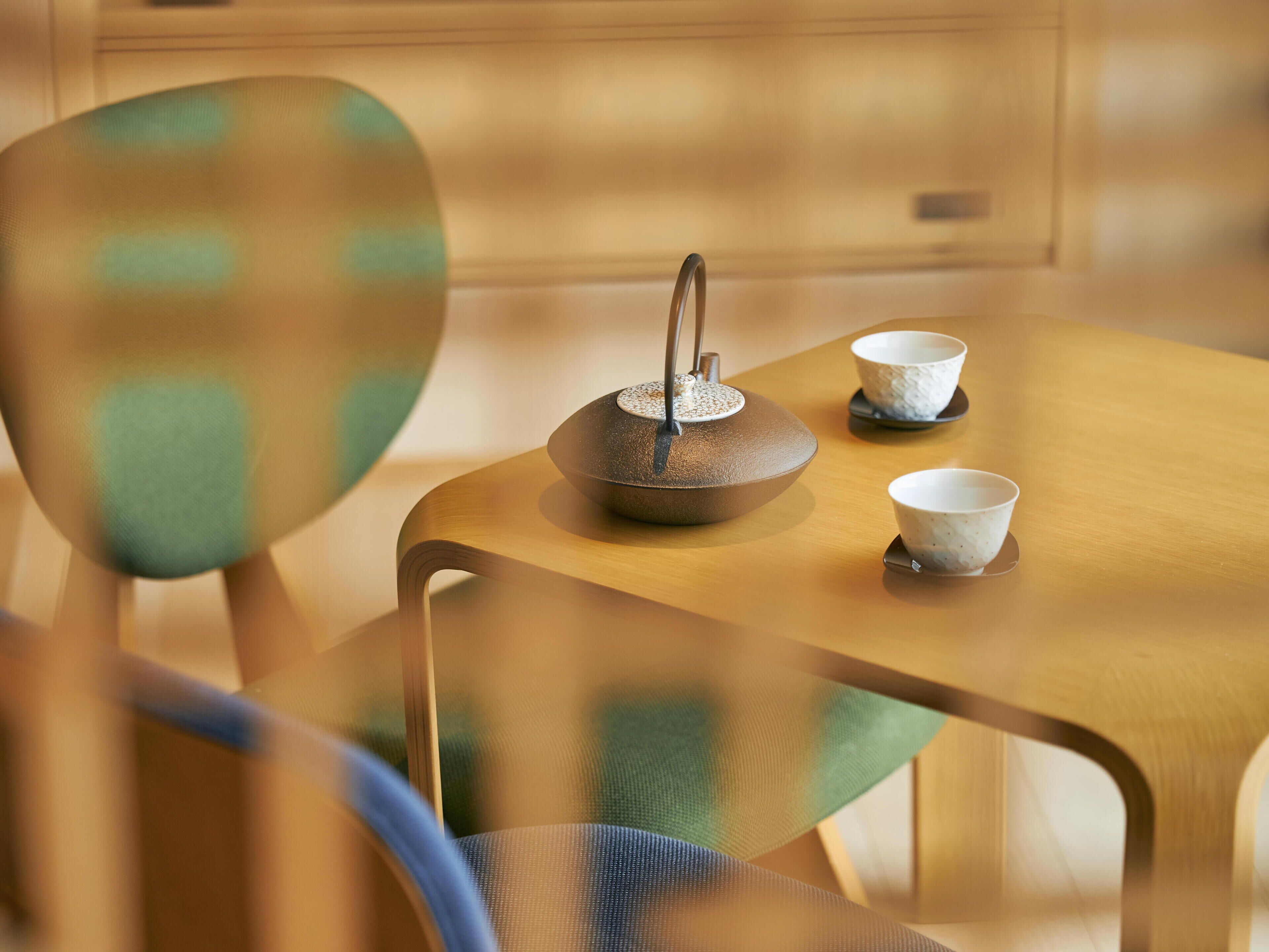 A wooden table with a teapot and two cups.