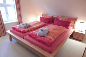 A double bed with pink bedding and two towels on each side.
