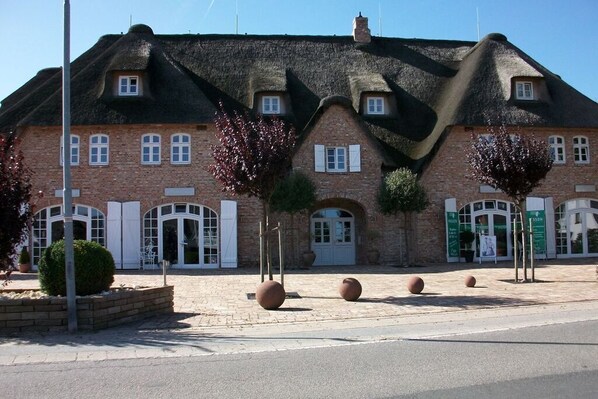 A traditional brick building with a thatched roof, arched windows, and a central entrance.