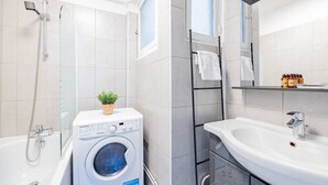 Un bagno moderno con lavatrice a incasso, una vasca, una doccia e un lavandino con specchio.