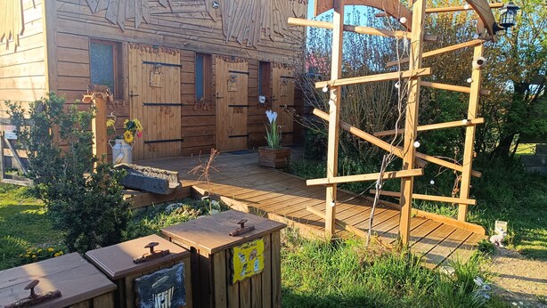 A wooden building with a rustic design, a wooden deck, and a wooden climbing structure. - Roulotte Ô Rêves Atypiques (Boucé)