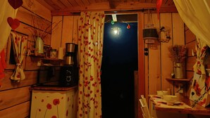 A cozy cabin interior with wooden walls, a kitchenette, a dining area, and a bed. - Roulotte Ô Rêves Atypiques (Boucé)