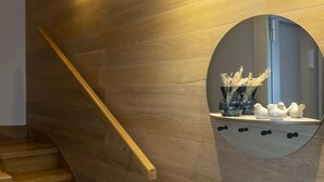 En trætrap med gelænder, en vægmonteret lampe og et rundt spejl med pynteting.