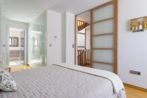 Una camera da letto con un letto, un armadio con ante scorrevoli in vetro e una scala in legno.
