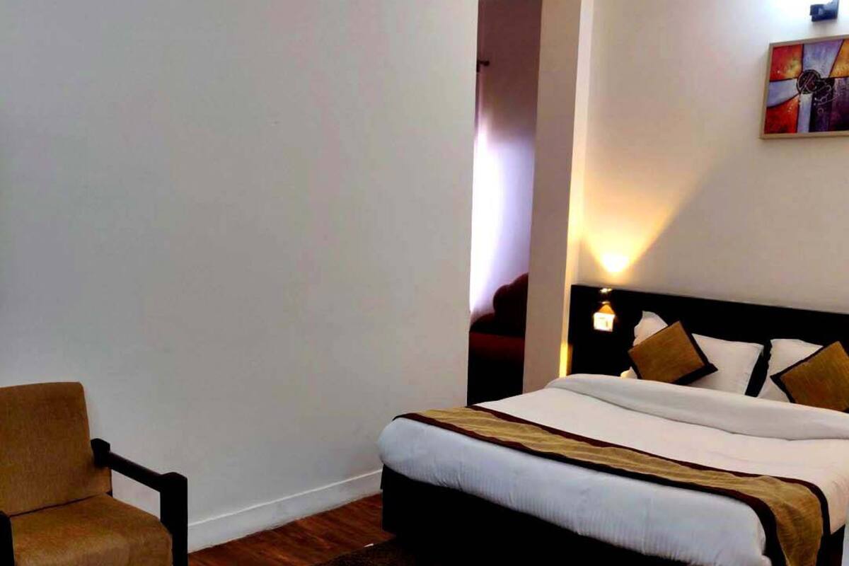 A bedroom with a bed, a chair, a nightstand, and a painting on the wall.