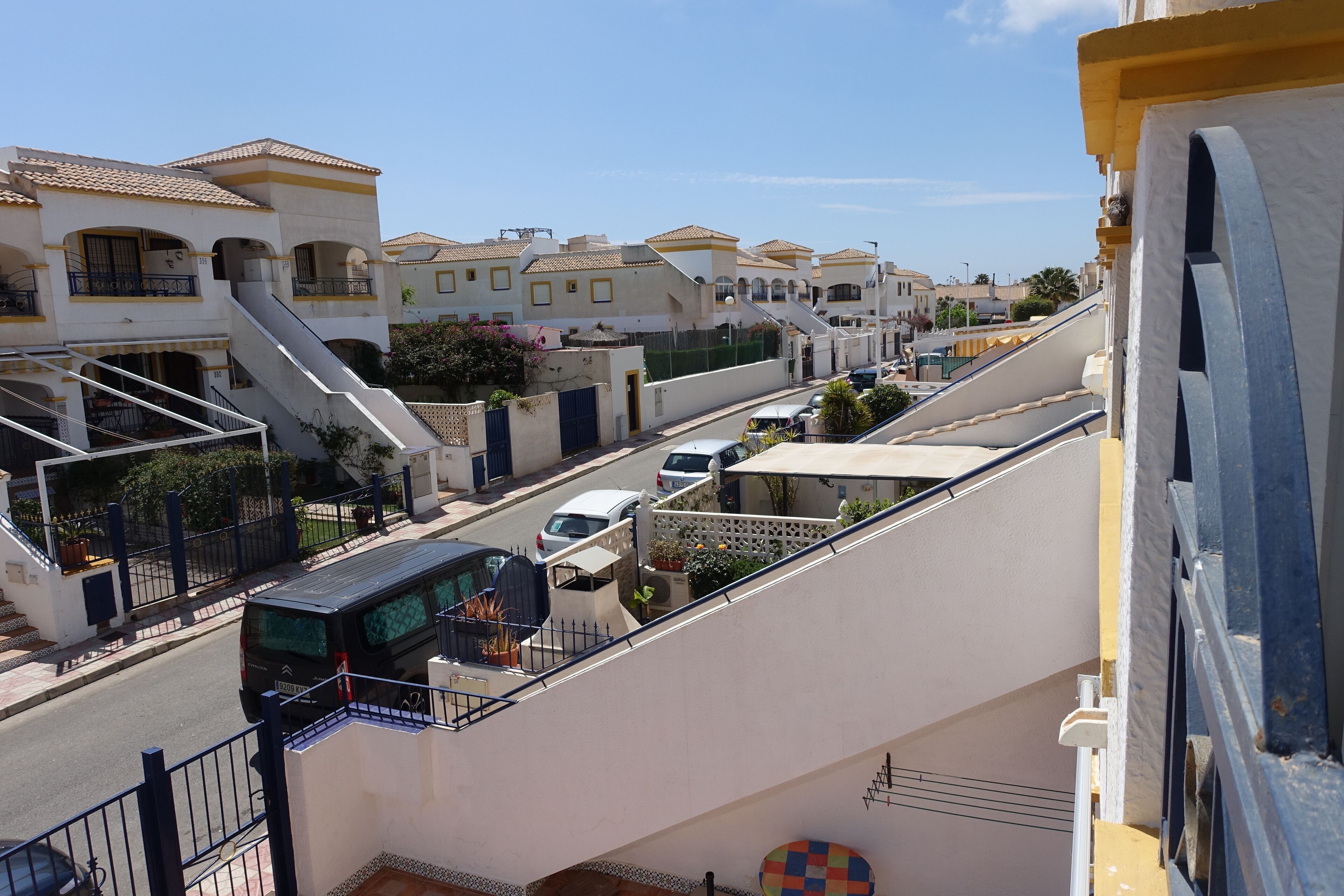 Eine Wohnstraße mit Häusern, einer Treppe und geparkten Autos.