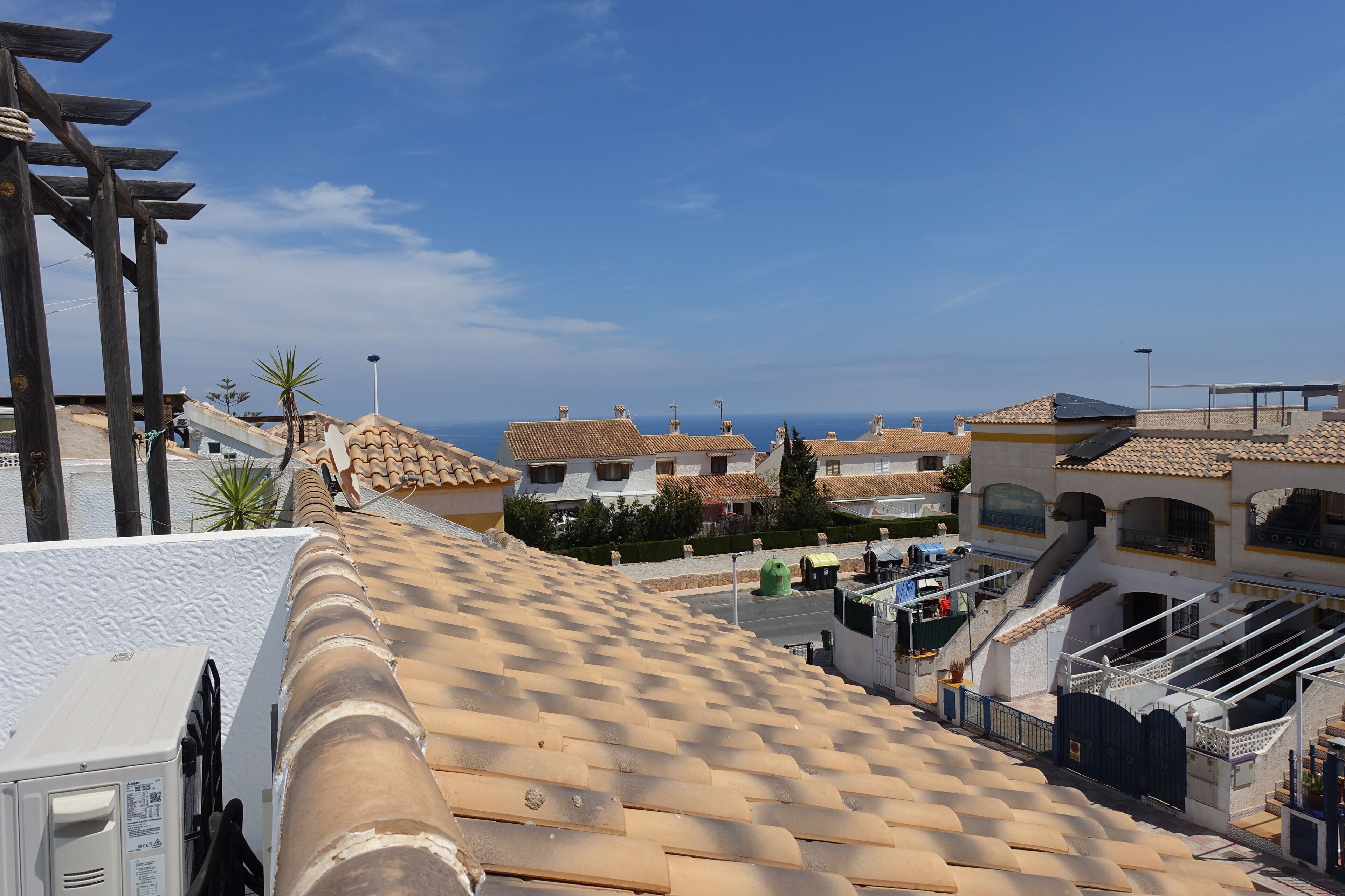 A rooftop terrace with a tiled roof, a pergola, and a view of the sea.