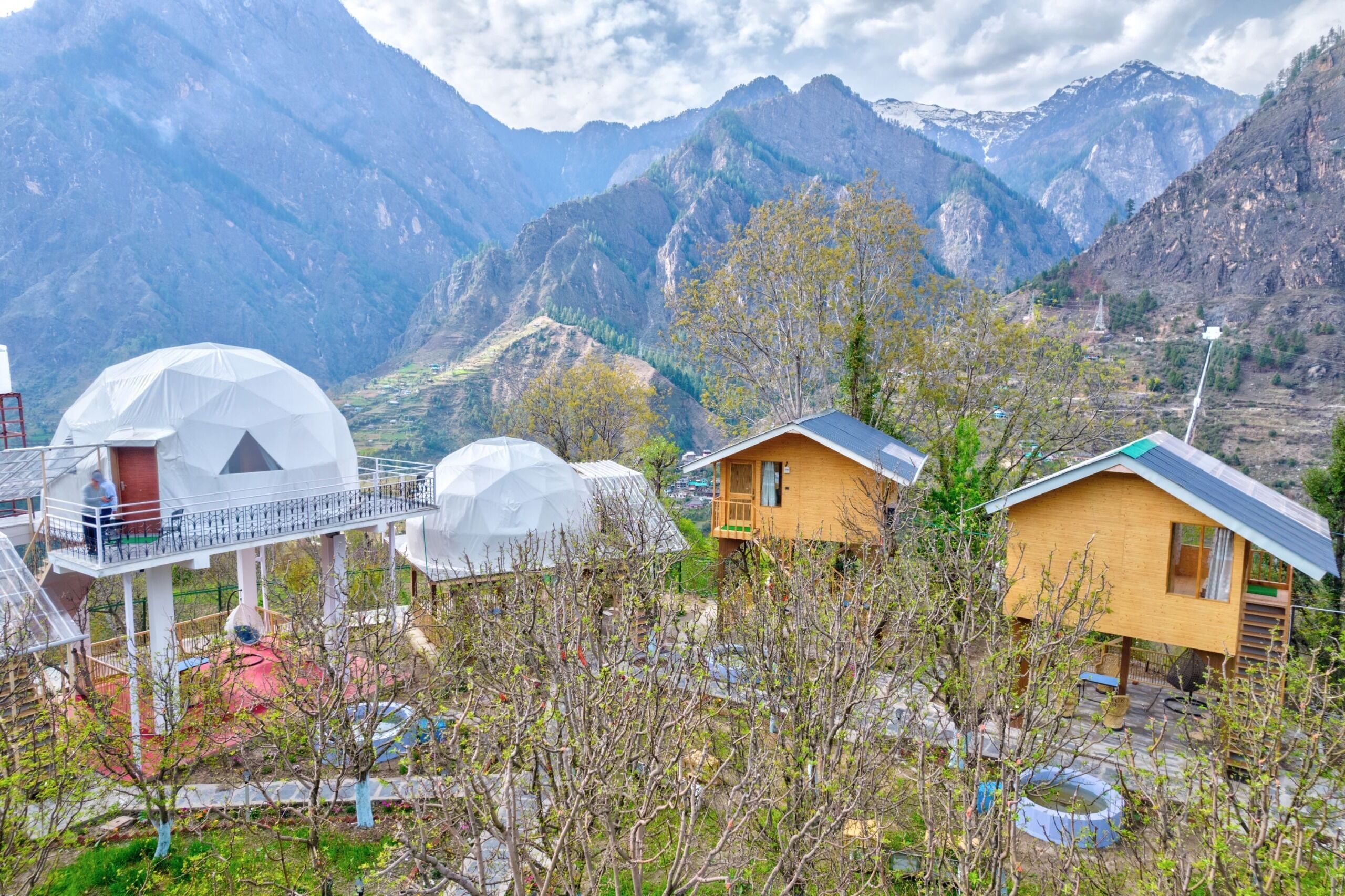 Un paisaje montañoso con una casa moderna y una estructura en forma de cúpula.