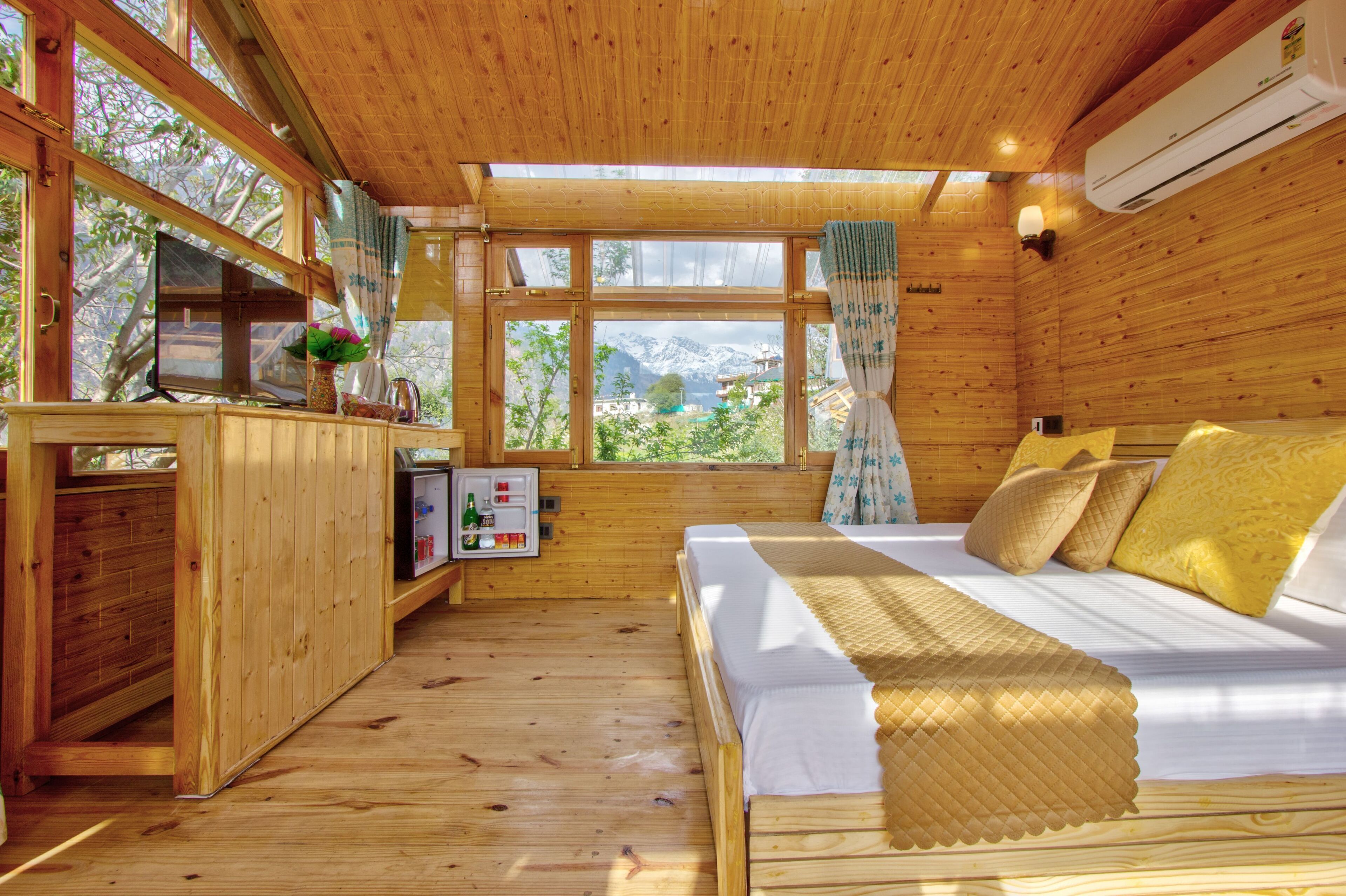 Una baita di legno con un letto, una scrivania e una finestra vista montagna.