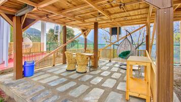 Un patio techado con suelo de piedra, mobiliario de madera y vistas al exterior.