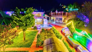 Un espacio exterior bien iluminado con un restaurante, una fuente y una zona de estar cubierta.