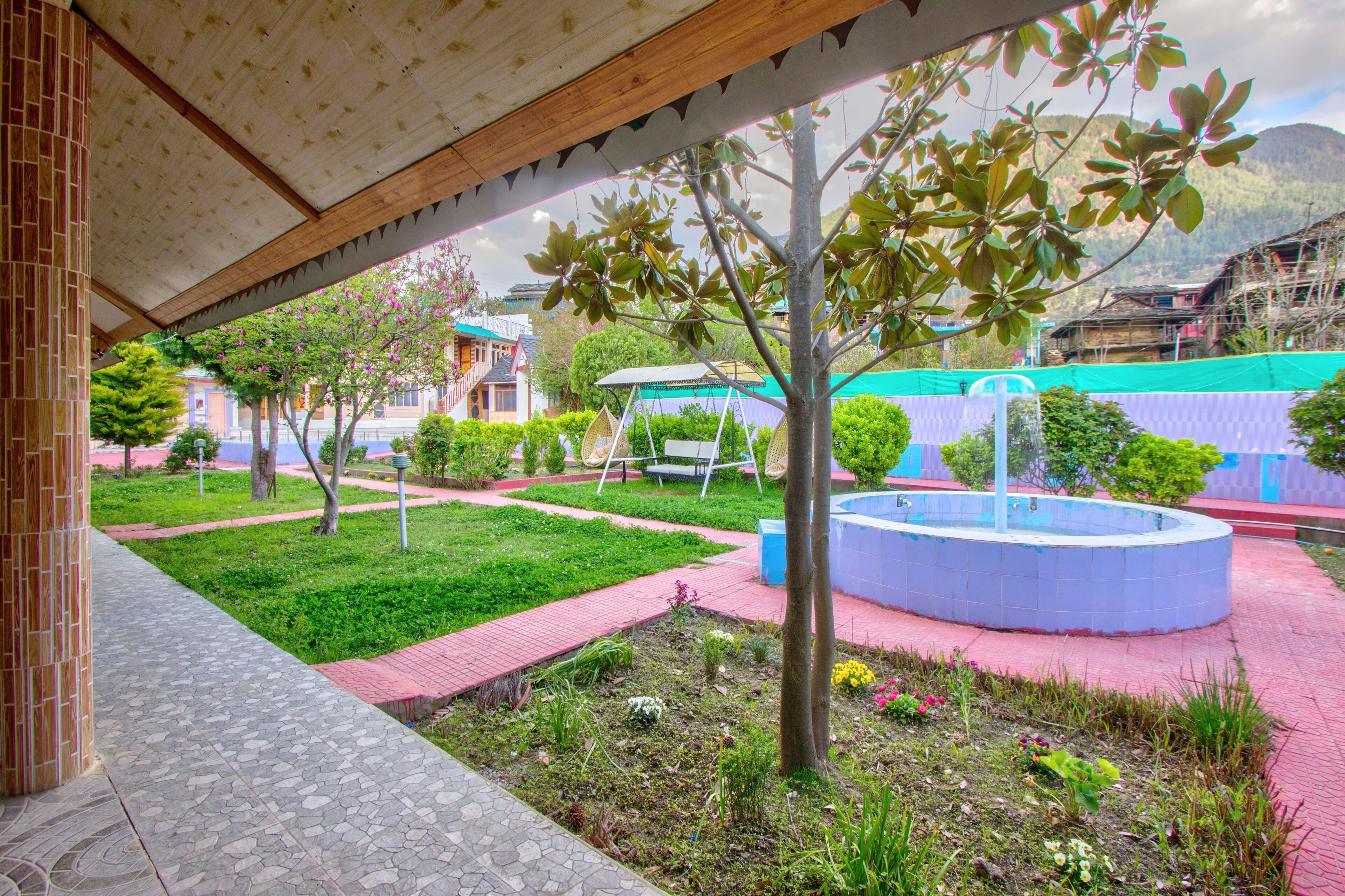 Un patio con una fuente, césped verde y un paseo cubierto.
