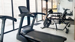 Un gimnasio con cintas de correr, mancuernas y equipo de ejercicio.