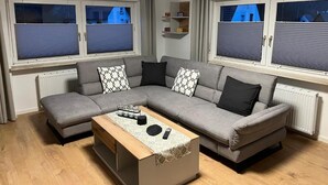 En moderne stue med en grå modulsofa, et træbord og en radiator.