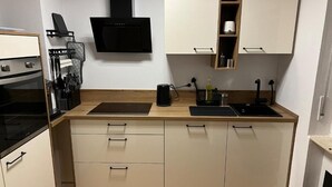 Et lille køkken med mikrobølgeovn, komfur og kaffemaskine.