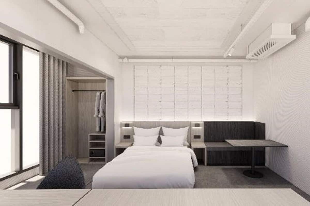 A modern hotel room with a large bed, a desk, and a seating area.