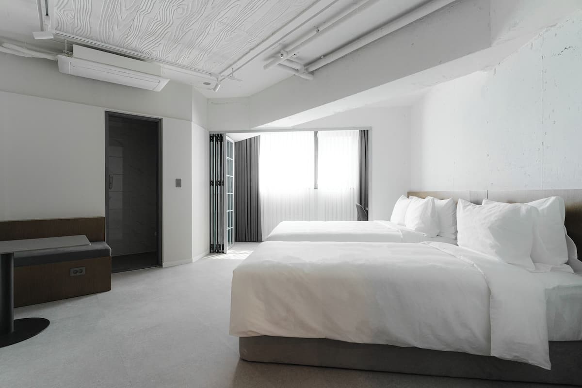 A modern hotel room with a large bed, a desk, and a wardrobe.