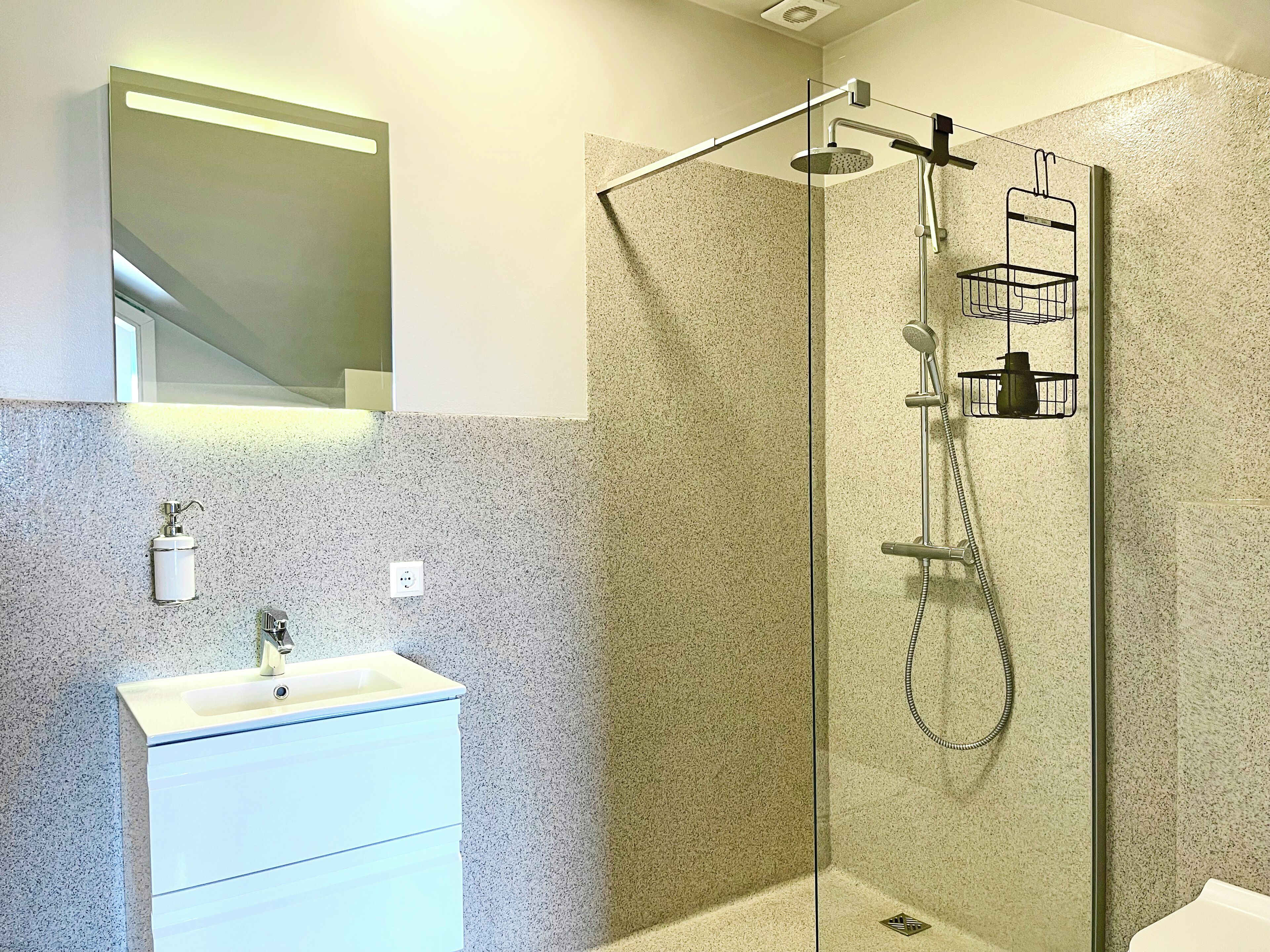 A modern bathroom with a glass-enclosed shower, a white sink, and a mirror above it.