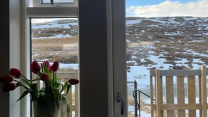 A wooden deck with a view of a snowy landscape through a door. - Lindarholl Guesthouse (Egilsstaðir)