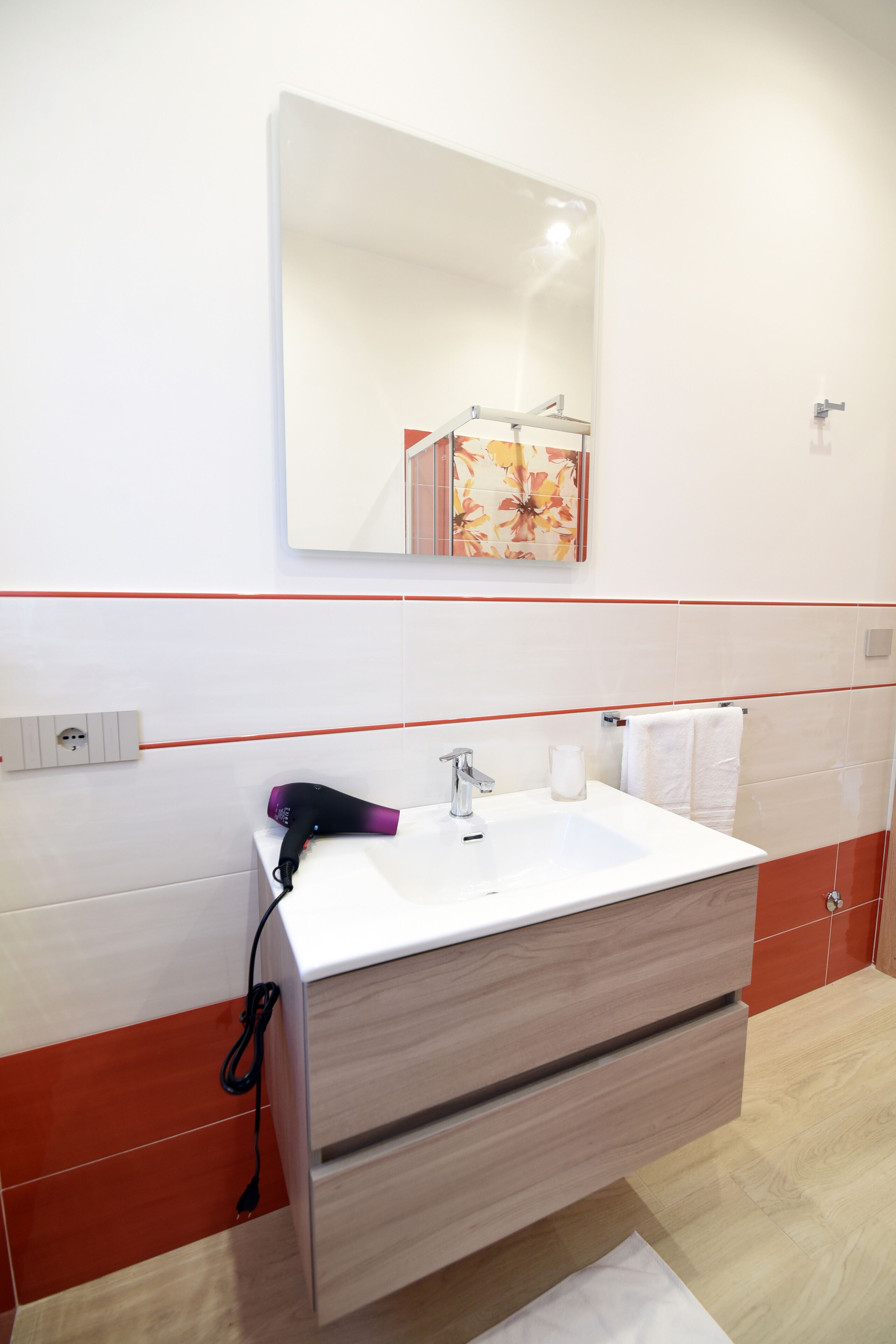 Un baño con lavamanos blanco, un espejo y un secador de pelo.