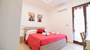 Ein Schlafzimmer mit einem Bett, einem Nachttisch, einem Sessel und zwei an der Wand befestigten Bildern.