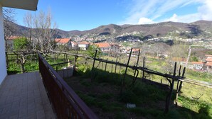 Ein Balkon mit Blick auf ein Hügeldorf, einem Holzzaun und einem strahlend blauen Himmel.