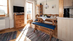 A cozy kitchen with wooden furniture, a television, and a dining area with a bench.