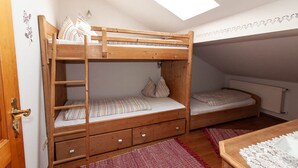 A bunk bed room with a skylight, a radiator, and a wooden door.