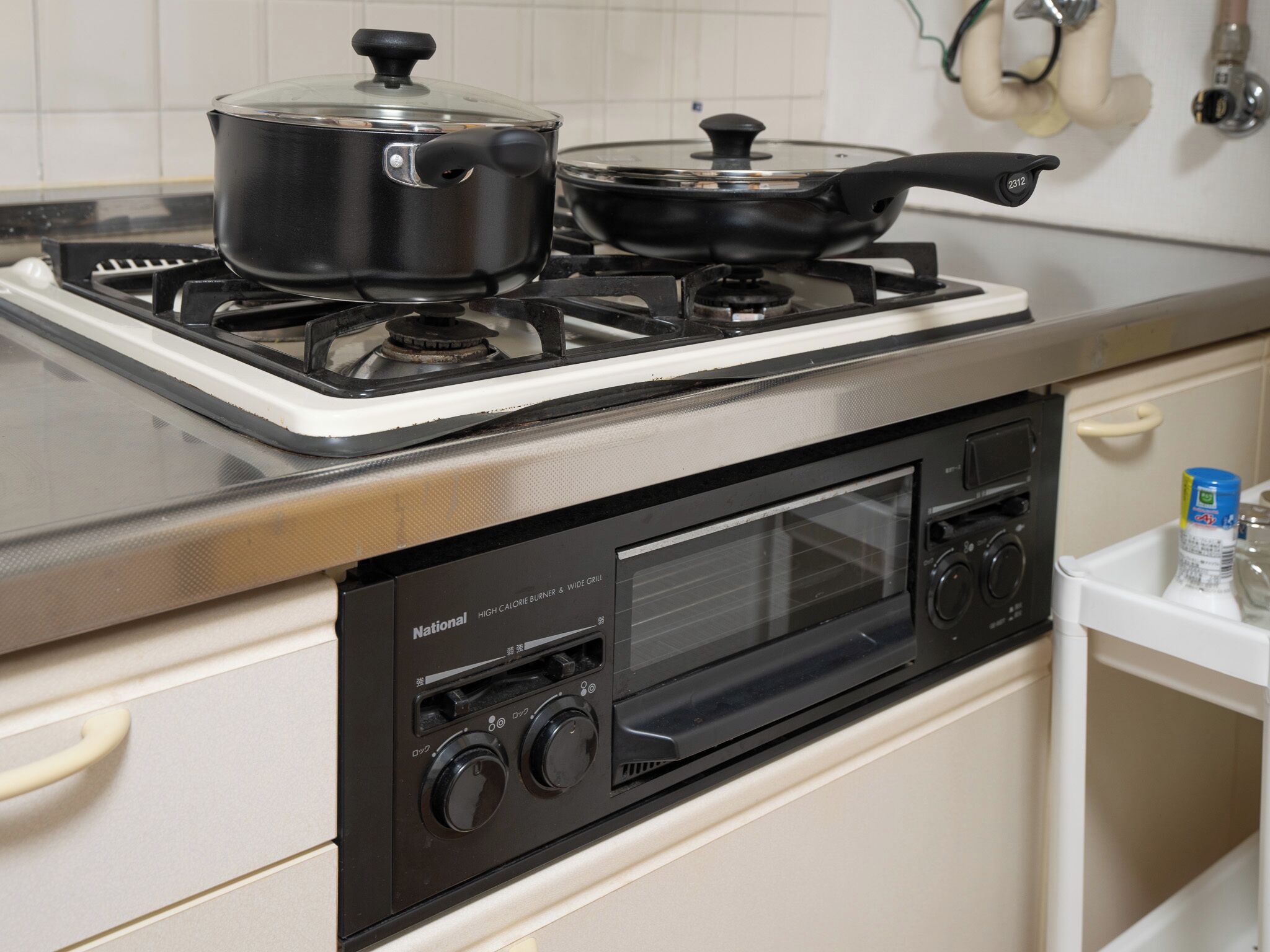 A kitchen with a gas stove, a microwave, and a pot on the stove.