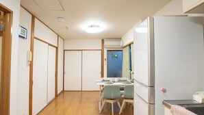 Une cuisine compacte comprenant un réfrigérateur, une table à manger avec des chaises et un placard avec une porte coulissante.