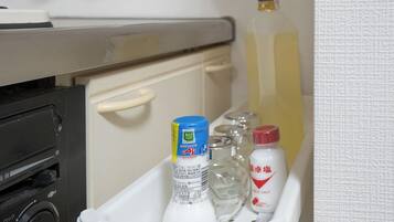 A storage compartment with a bottle of Aji Shoyu, a bottle of clear liquid, and a bottle of table salt.